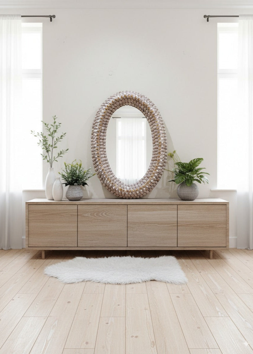 Wooden sideboard with decorative mirror and plants in a bright room.
