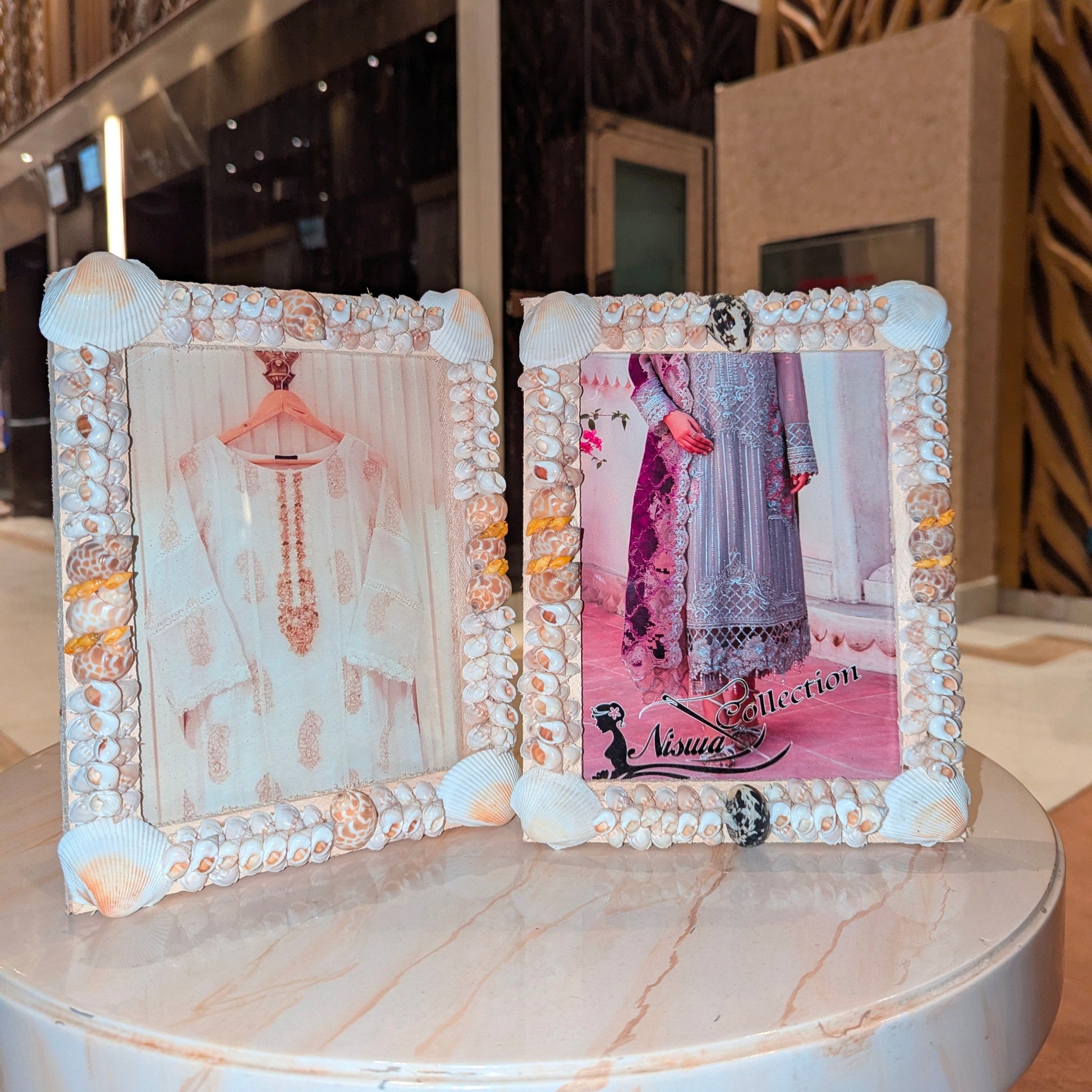 Two decorative picture frames with shell embellishments on a marble surface.